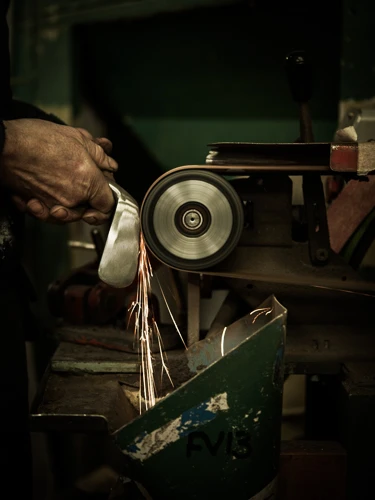A clubmaker grinding an iron head on a wheel, sparks falling