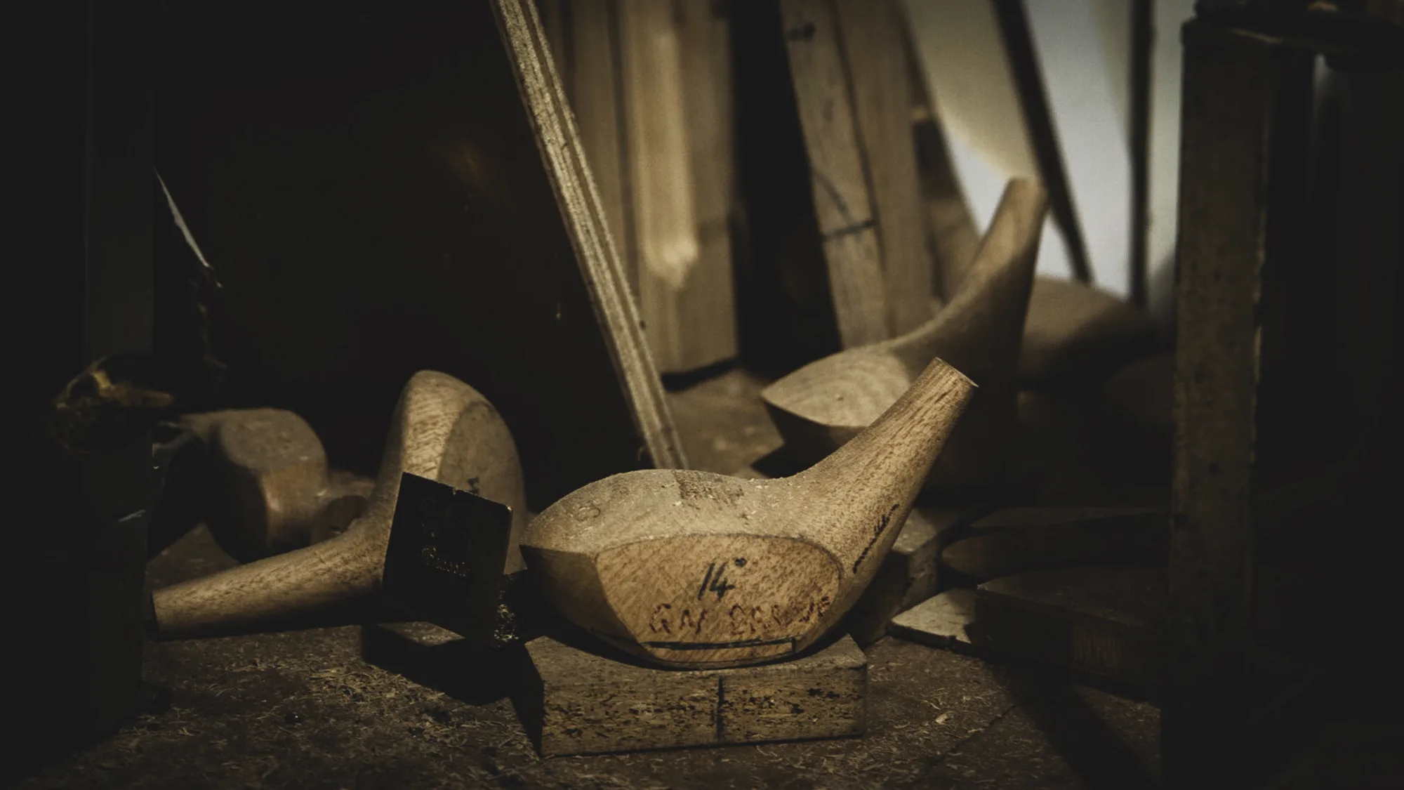 Turned wooden club heads resting on a workshop bench